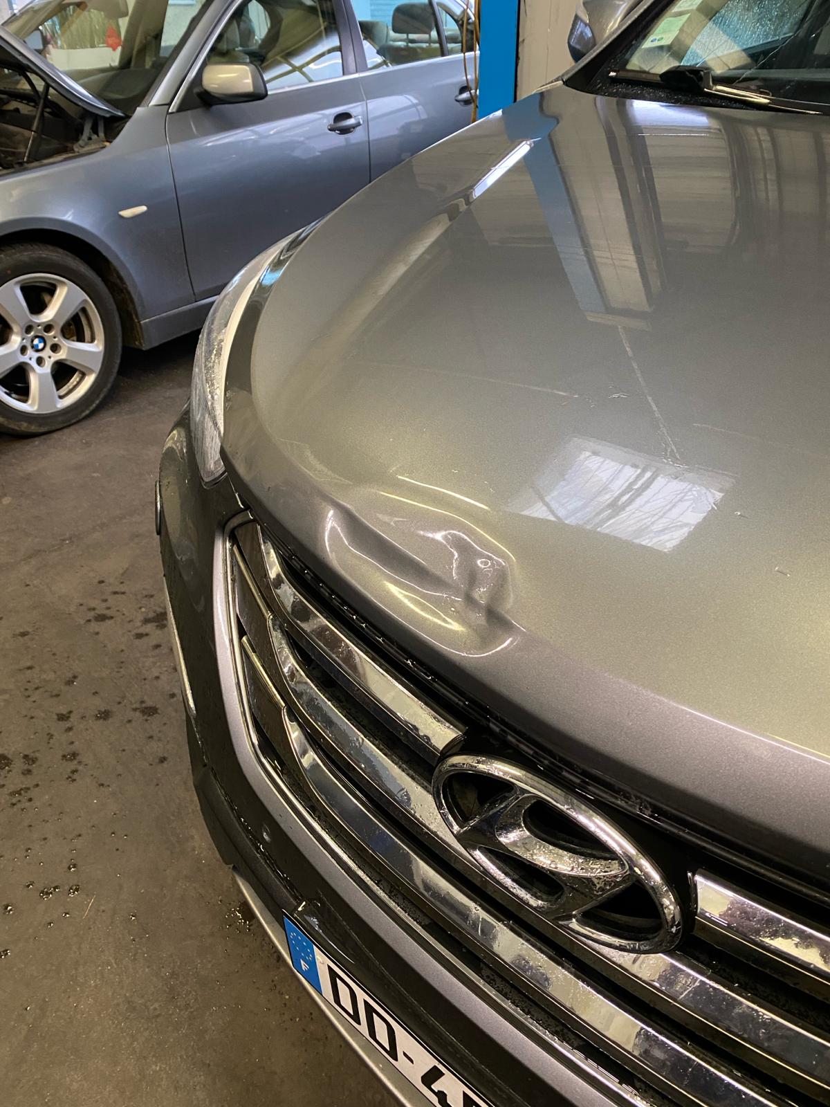 Capot d'un SUV gris enfoncé juste au-dessus de la calandre