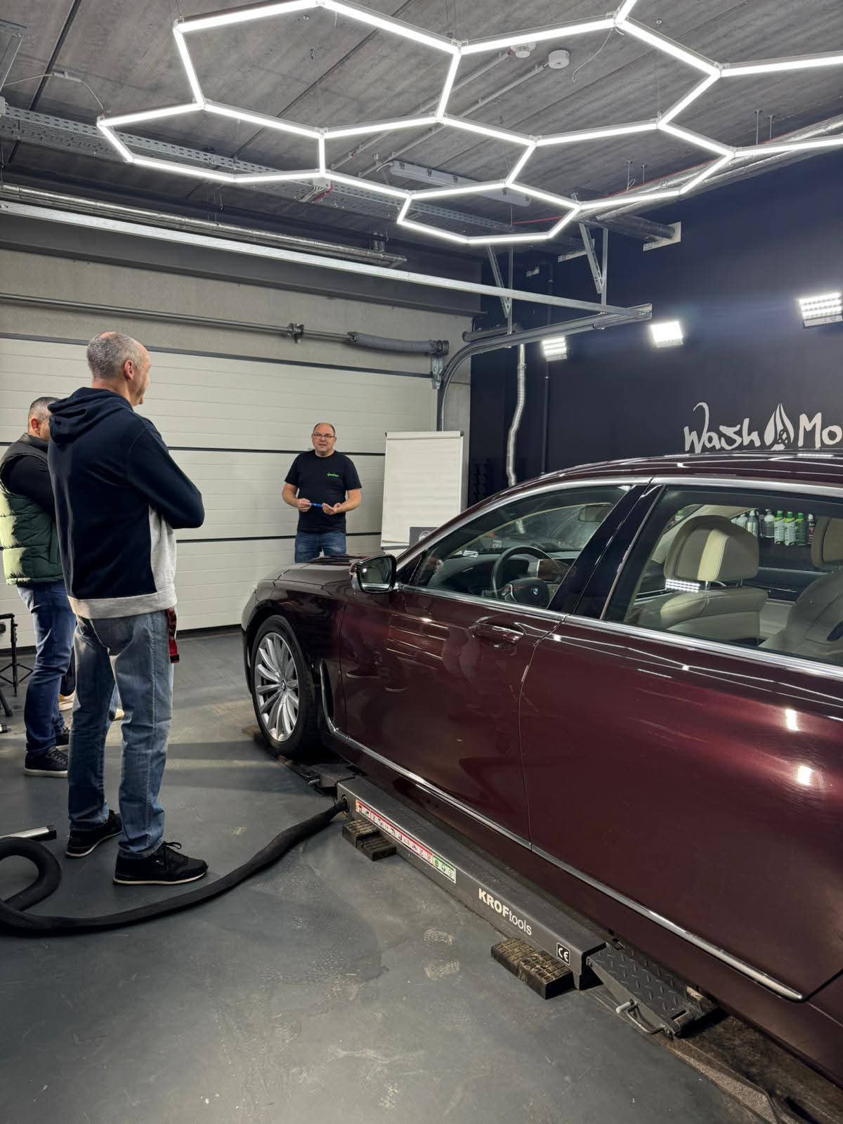 Session de formation SW Detailing : explication théorique devant une berline en baie de detailing