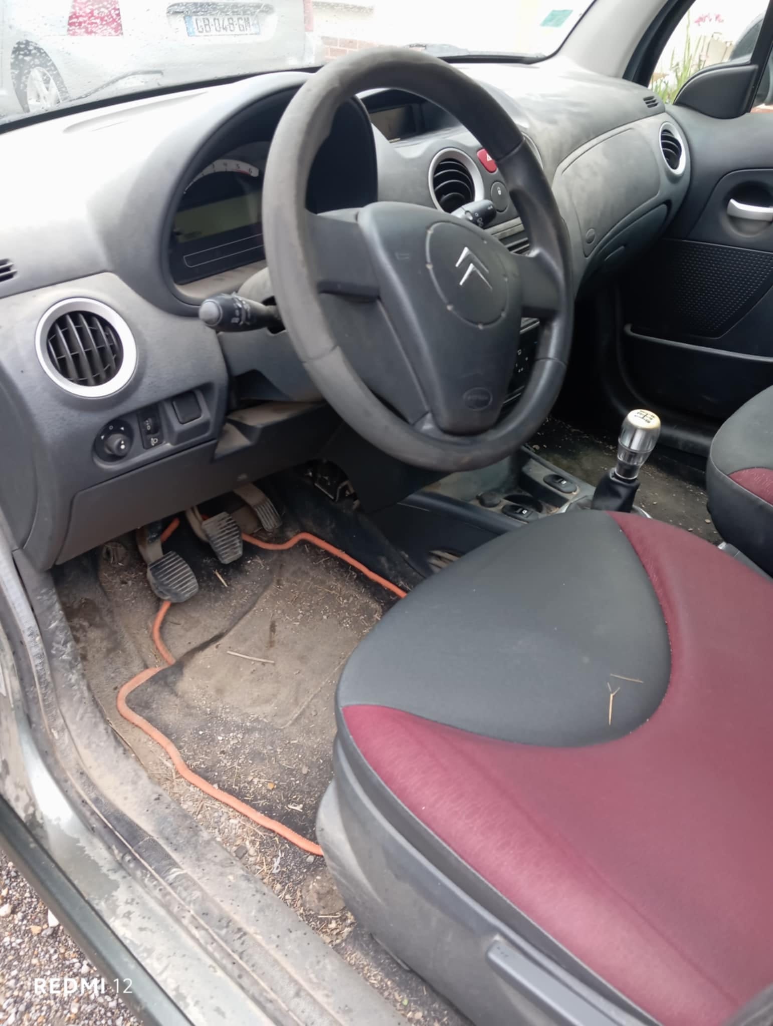 Tableau de bord poussiéreux et plancher souillé d'une Citroën C3 avant intervention