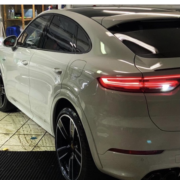 Porsche Cayenne coupé gris vu de l'arrière, feux arrière allumés